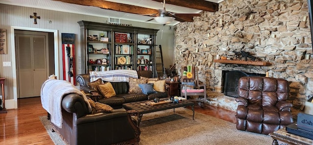 living room featuring ceiling fan, beam ceiling, wood-type flooring, and a fireplace