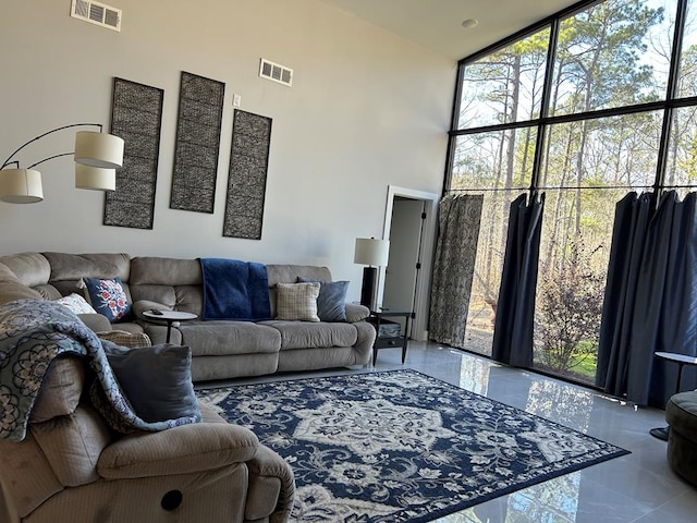 living area featuring expansive windows, a high ceiling, and visible vents