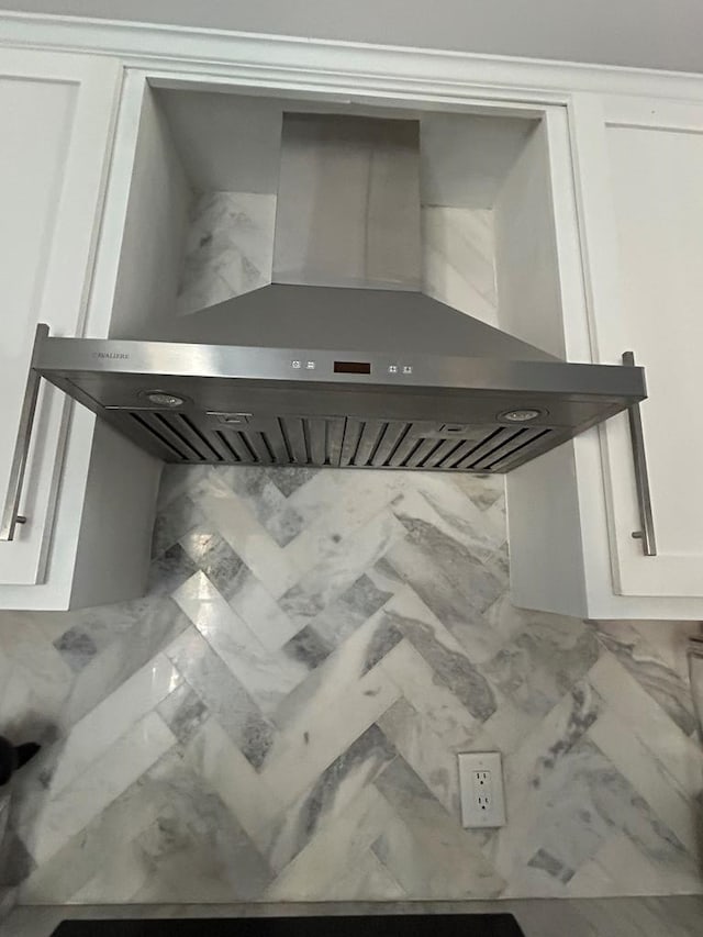 interior details featuring white cabinetry and wall chimney range hood