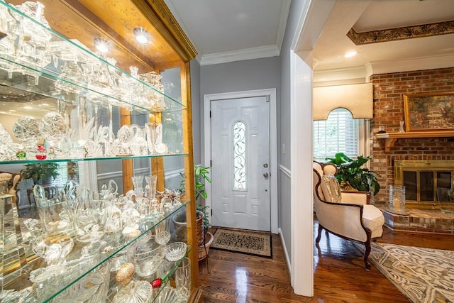 foyer featuring hardwood / wood-style flooring, a brick fireplace, and ornamental molding