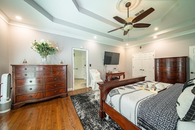 bedroom with a closet, a tray ceiling, ceiling fan, and hardwood / wood-style flooring