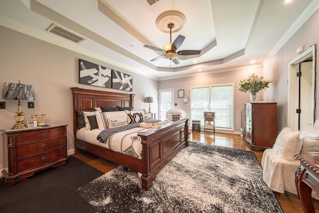 bedroom with ceiling fan, dark hardwood / wood-style floors, crown molding, and a tray ceiling