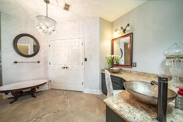 bathroom with tile patterned flooring, vanity, and an inviting chandelier