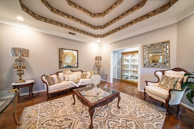 living room featuring wood-type flooring, a raised ceiling, and ornamental molding