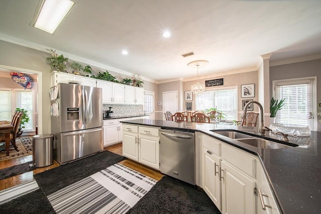 kitchen featuring appliances with stainless steel finishes, white cabinetry, ornamental molding, and wood-type flooring