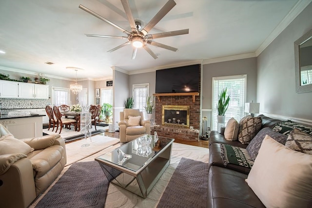 living room with a wealth of natural light, light hardwood / wood-style flooring, ceiling fan with notable chandelier, and ornamental molding