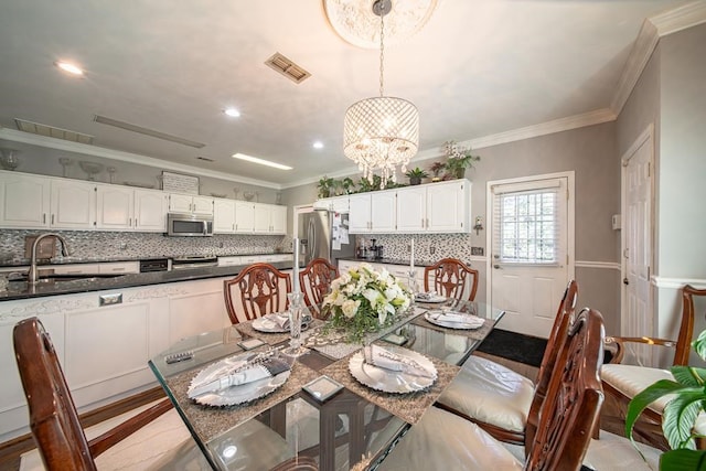 dining space with a notable chandelier, crown molding, sink, and light hardwood / wood-style flooring