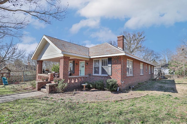 bungalow-style home featuring a chimney, a front yard, fence, and brick siding