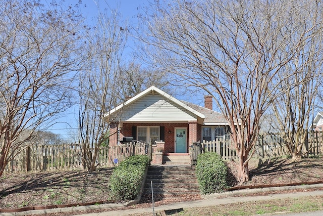 bungalow with covered porch, a chimney, and brick siding