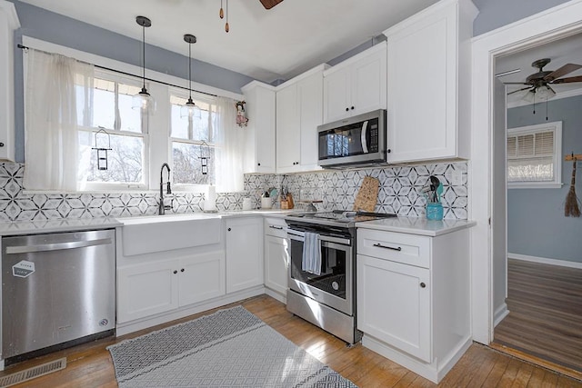 kitchen featuring ceiling fan, stainless steel appliances, a sink, and light countertops