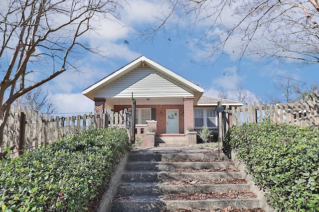 bungalow-style house featuring fence, a porch, and brick siding