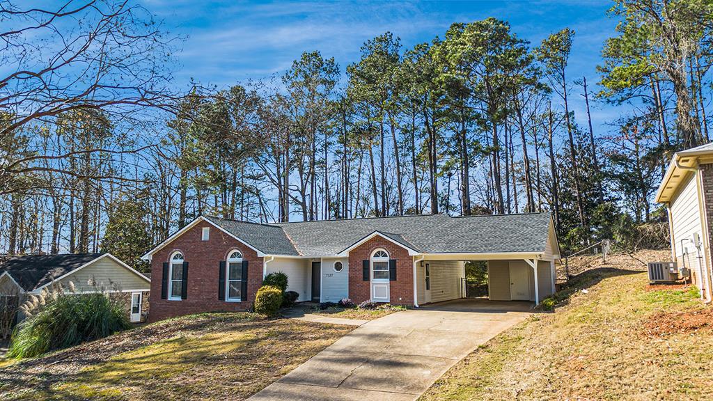 single story home with a carport, central air condition unit, and a front lawn