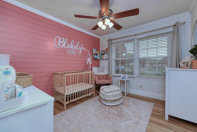 4502 Northwood Ave, Columbus, GA 31907 - bedroom with a nursery area, ornamental molding, light wood-type flooring, a ceiling fan, and wooden walls