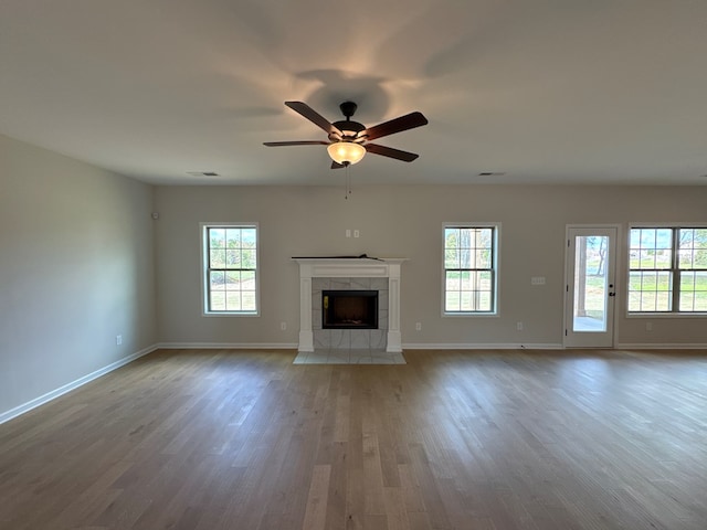 unfurnished living room featuring a fireplace, ceiling fan, light hardwood / wood-style flooring, and a healthy amount of sunlight