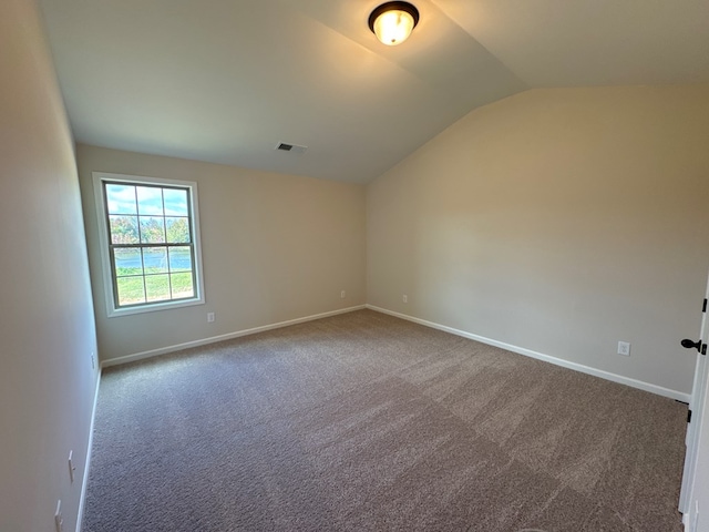 carpeted spare room featuring vaulted ceiling