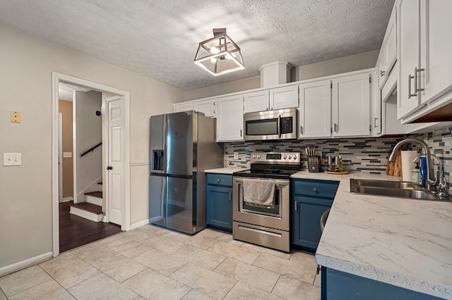 701 Crestline Dr, Columbus, GA 31907 - kitchen with stainless steel appliances, blue cabinets, backsplash, light countertops, and a textured ceiling