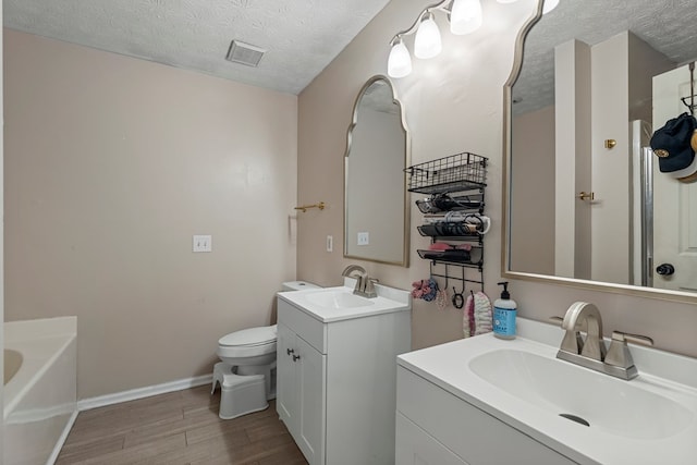 701 Crestline Dr, Columbus, GA 31907 - full bathroom featuring a textured ceiling, wood finished floors, two vanities, and a garden tub
