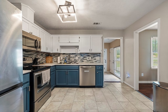 701 Crestline Dr, Columbus, GA 31907 - kitchen featuring appliances with stainless steel finishes, blue cabinetry, decorative backsplash, light countertops, and a textured ceiling