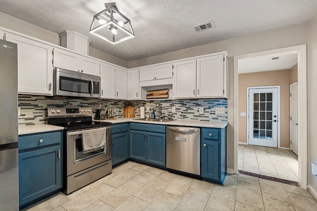 701 Crestline Dr, Columbus, GA 31907 - kitchen featuring stainless steel appliances, blue cabinets, light countertops, backsplash, and a textured ceiling