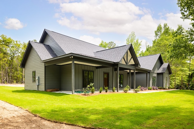 back of property with a shingled roof, board and batten siding, and a lawn
