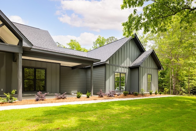 view of side of property featuring board and batten siding, roof with shingles, and a lawn