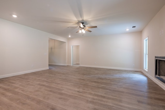 unfurnished living room with ceiling fan, a fireplace, recessed lighting, wood finished floors, and baseboards