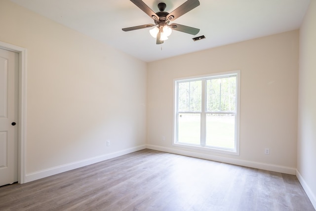 spare room with baseboards, wood finished floors, and ceiling fan