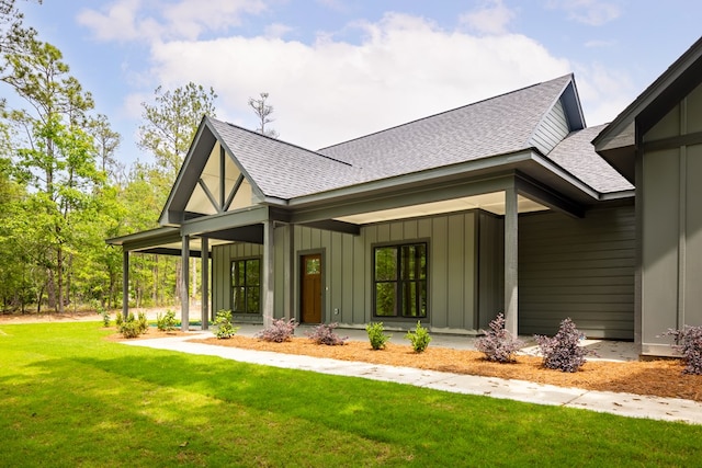 view of front facade featuring roof with shingles, board and batten siding, a front lawn, and a porch