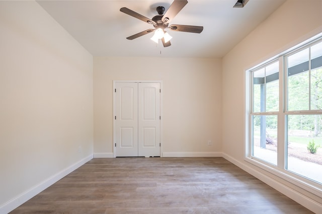 empty room with healthy amount of natural light, wood finished floors, and baseboards