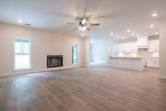 unfurnished living room featuring ceiling fan, baseboards, light wood-style flooring, recessed lighting, and a fireplace