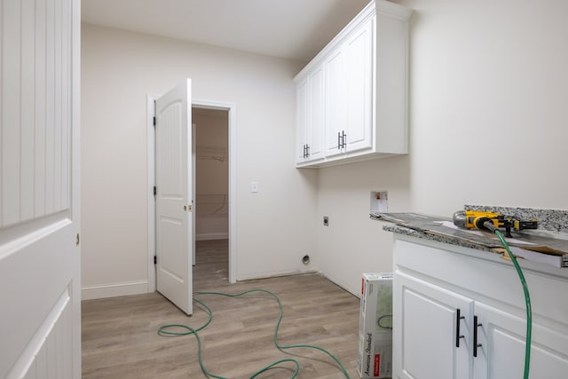 clothes washing area with electric dryer hookup, washer hookup, light wood-style floors, and cabinet space