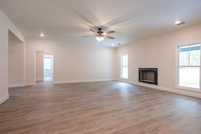unfurnished living room featuring healthy amount of natural light, a fireplace, ceiling fan, light wood-style floors, and recessed lighting