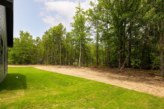 view of grassy yard featuring a view of trees