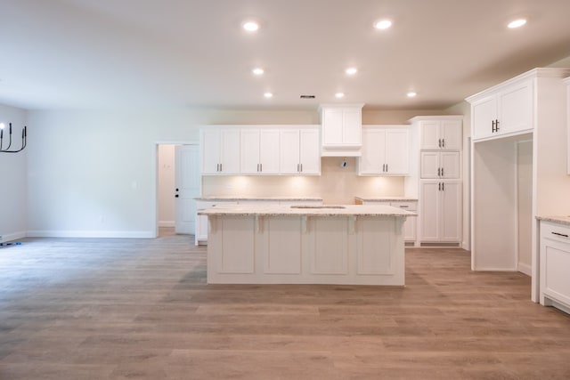 kitchen with a center island, baseboards, white cabinets, light wood-style floors, and recessed lighting