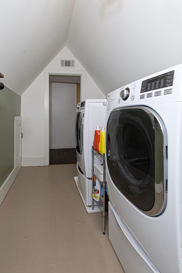 clothes washing area with visible vents, washer and clothes dryer, and laundry area