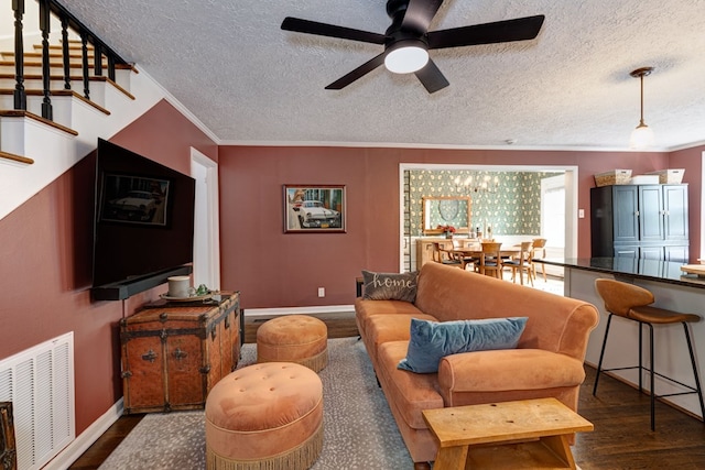 living area featuring a textured ceiling, visible vents, dark wood-style floors, and ceiling fan