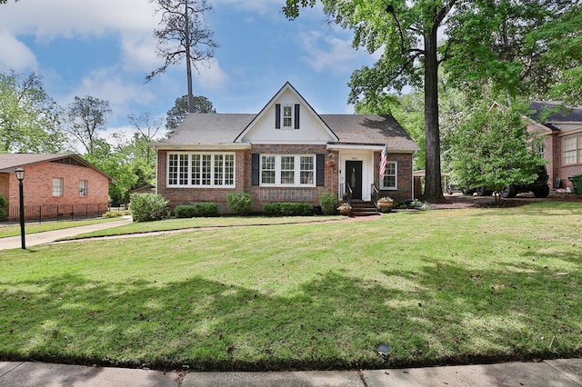view of front of property featuring brick siding, fence, and a front yard