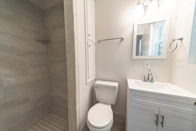 bathroom with vanity, toilet, and a tile shower