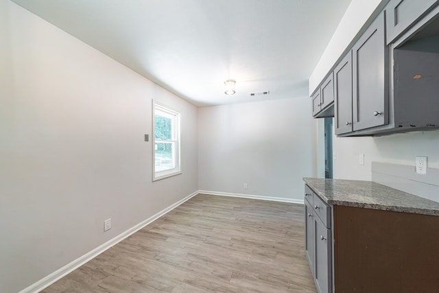 interior space featuring light hardwood / wood-style flooring, gray cabinetry, and dark stone countertops