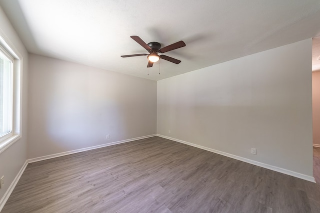 empty room featuring ceiling fan, plenty of natural light, and dark hardwood / wood-style floors