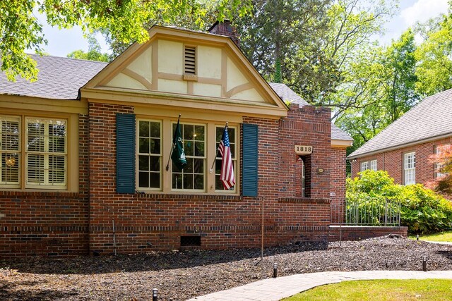view of side of home featuring crawl space, a shingled roof, and brick siding