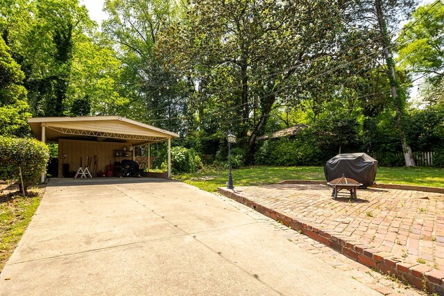 view of patio featuring a carport, concrete driveway, and an outdoor fire pit