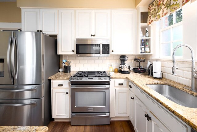 kitchen with white cabinets, tasteful backsplash, stainless steel appliances, and a sink