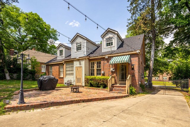 cape cod home featuring a fire pit, brick siding, and fence