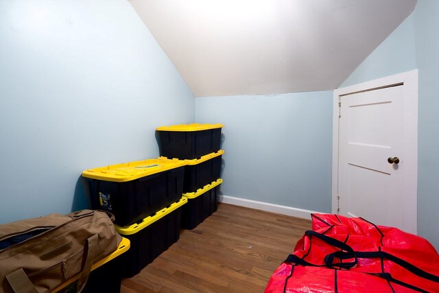 bedroom featuring lofted ceiling, baseboards, and wood finished floors