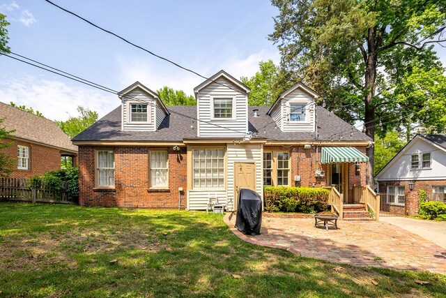 rear view of house with fence, a lawn, brick siding, and a patio area