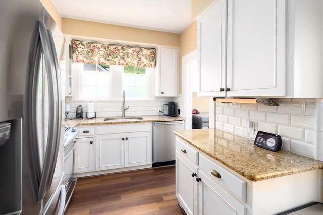 kitchen featuring white cabinets, dark wood finished floors, a sink, tasteful backsplash, and appliances with stainless steel finishes