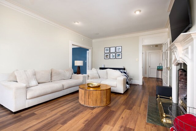 living area with crown molding, a fireplace with raised hearth, baseboards, dark wood-style flooring, and recessed lighting