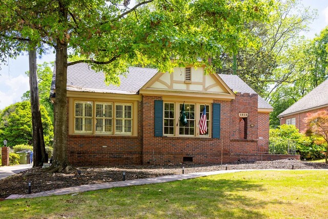 view of side of property with a lawn, a shingled roof, brick siding, and crawl space
