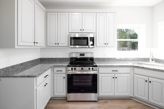 kitchen with white cabinetry, appliances with stainless steel finishes, sink, and light hardwood / wood-style flooring